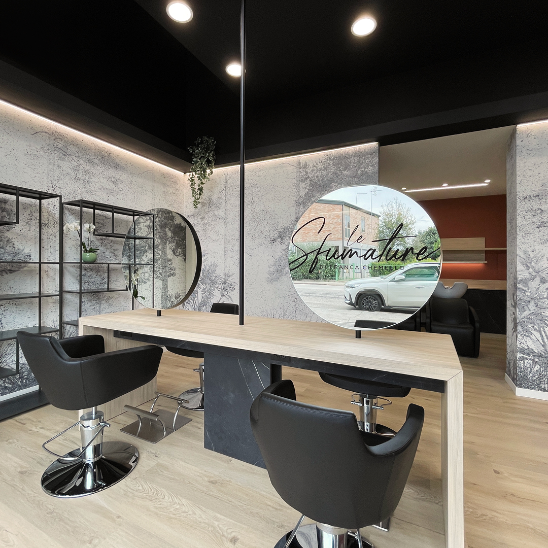 Immagine dell'area stilistica con pareti color mattone, poltrone nere e specchi. Mobili in legno 